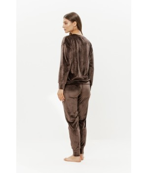 Model wearing soft velour loungewear set in relaxed seated pose
